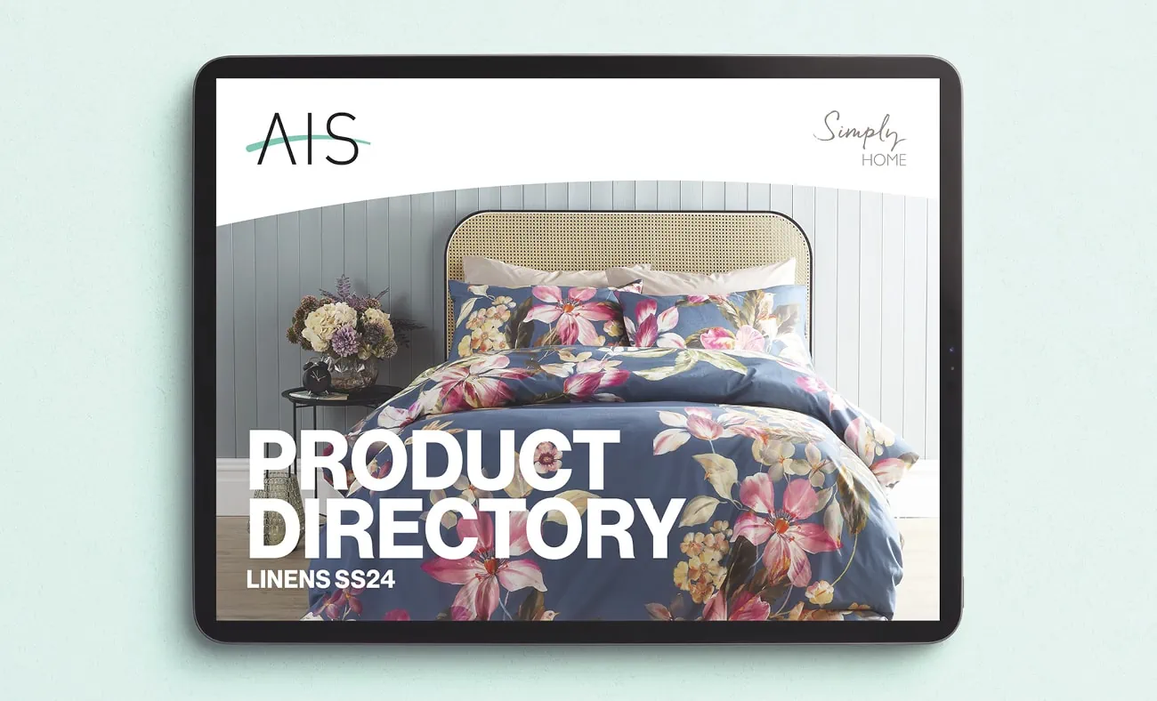 A tablet displaying a digital catalog cover for “AIS Simply Home.” The cover features a product directory titled “LINENS SS24” and showcases a neatly made bed with floral-patterned bedding.