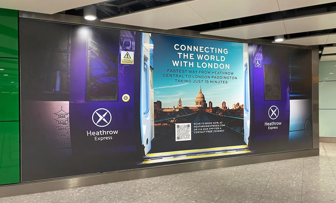 A large advertisement for Heathrow Express. The ad promotes the Heathrow Express service, highlighting it as the fastest way to travel from Heathrow to London Paddington, taking just 15 minutes. The background features a train door opening to reveal a view of London’s skyline.
