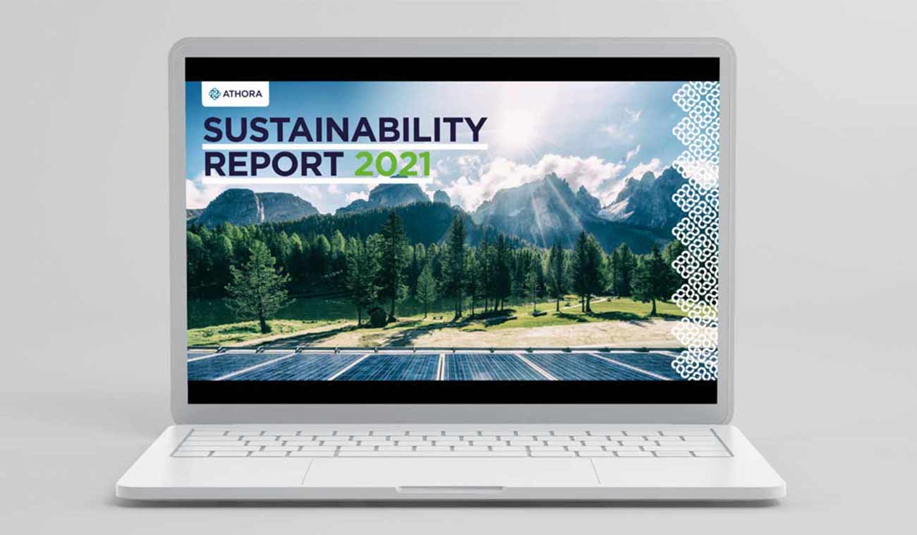A laptop displaying the cover of Athora's 2021 Sustainability Report, featuring a scenic landscape of mountains and solar panels.