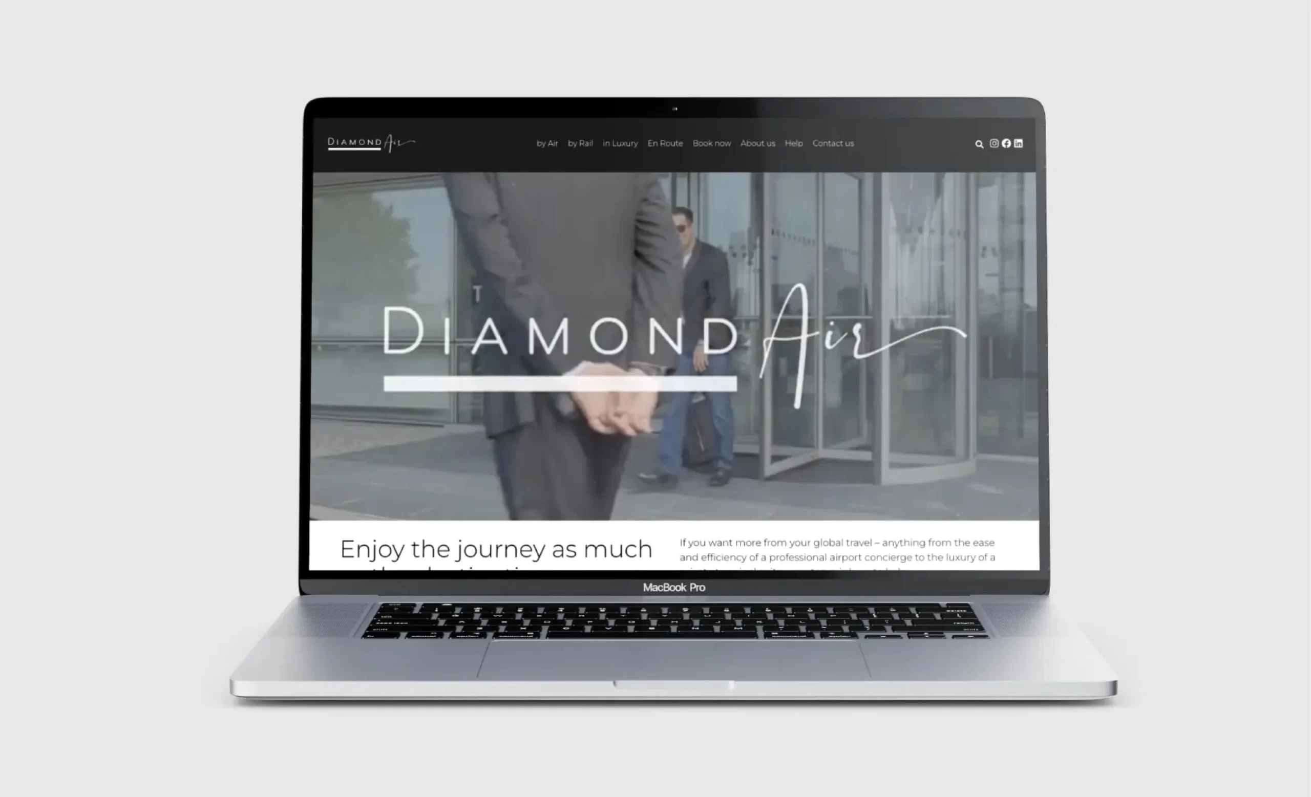 A laptop screen displaying the website for “DiamondAir.” The website’s homepage features a background image of a well-dressed man in a suit. The text “DiamondAir” is prominently displayed in stylish, elegant typography across the centre of the screen. Below the logo, the tagline reads, “Enjoy the journey as much as the destination.” The website menu at the top includes options like “by Air,” “by Rail,” “in Luxury,” and “En Route.”