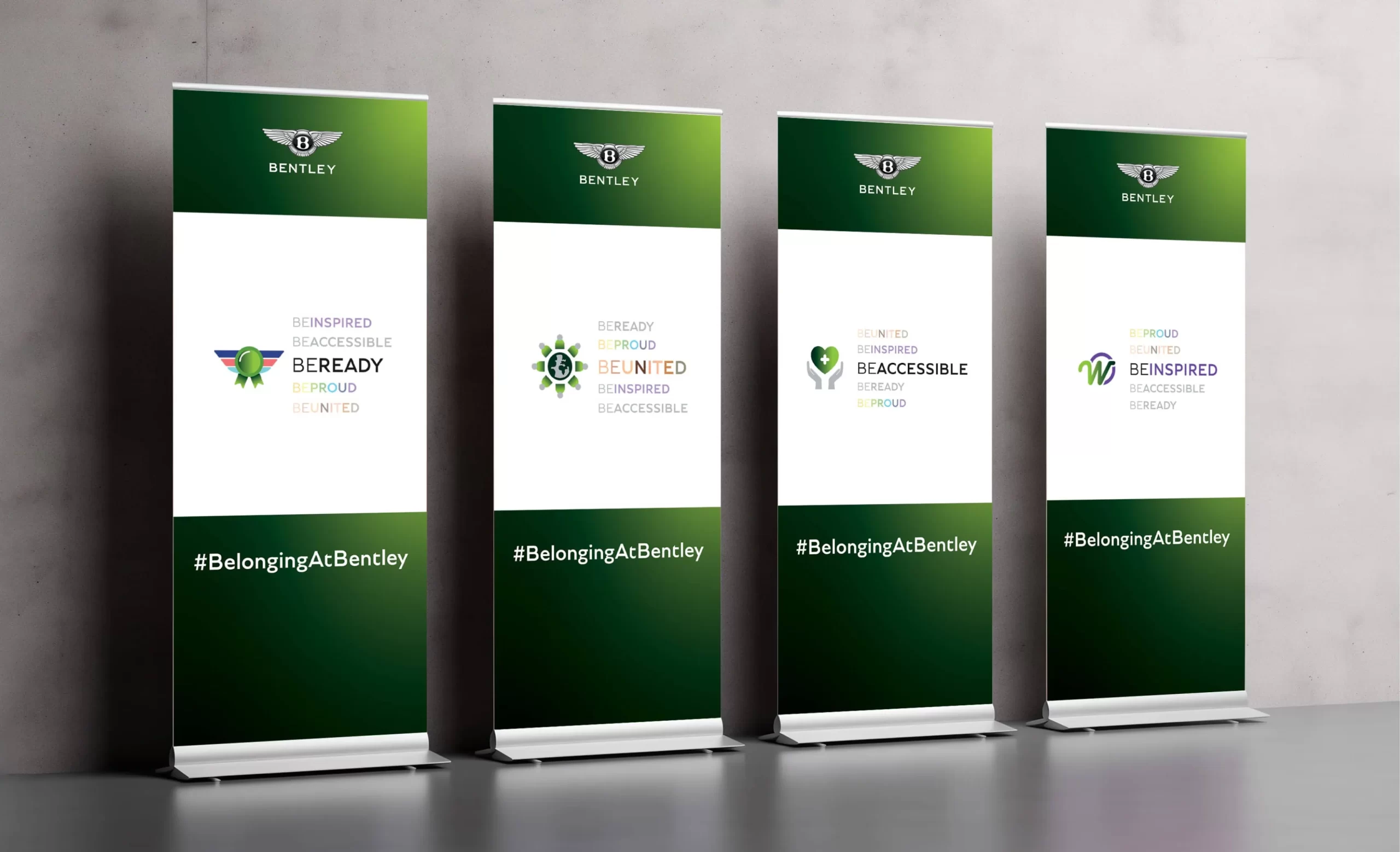 Four vertical banners displayed in a row, each featuring the Bentley logo at the top. The banners promote Bentley’s internal initiatives with phrases like “BE READY,” “BE UNITED,” “BE ACCESSIBLE,” and “BE INSPIRED,” each associated with different symbols and colour schemes.