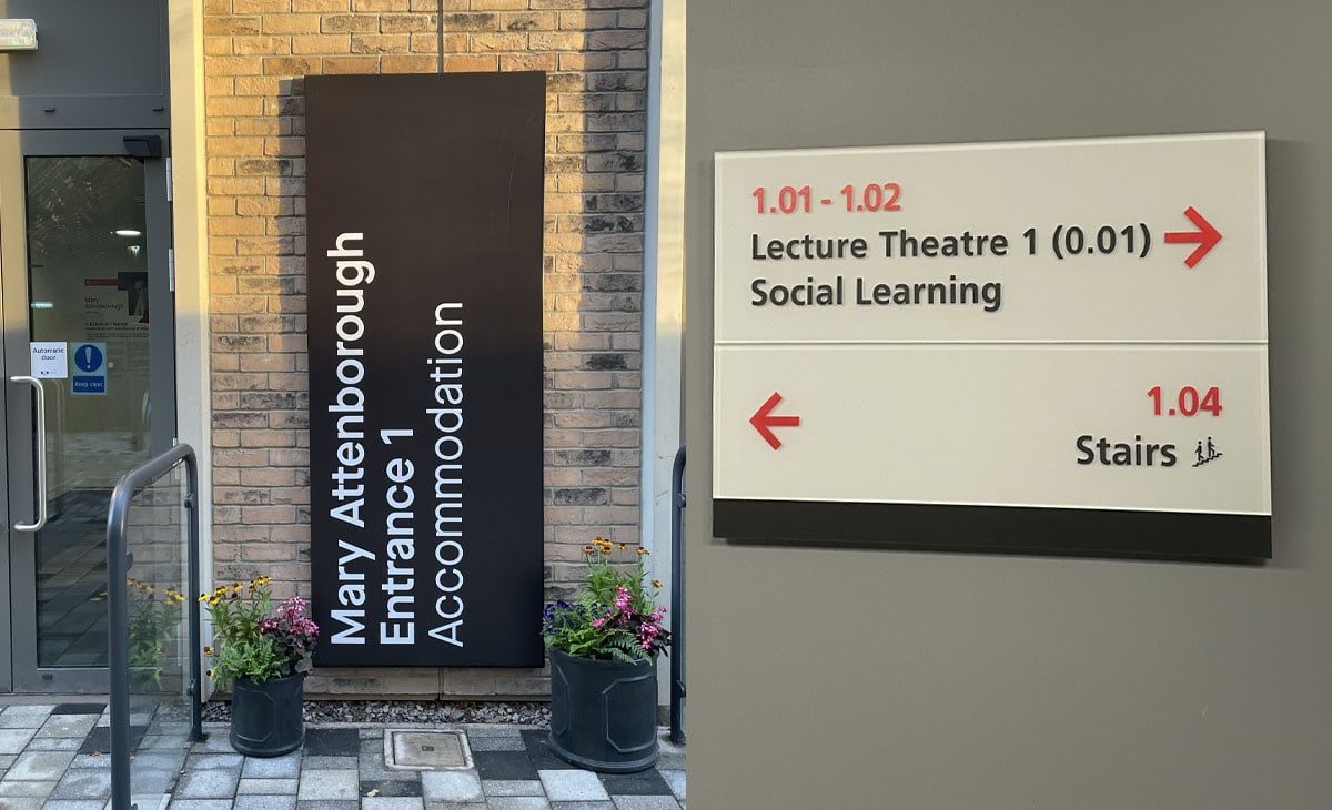 The image shows two different signs. On the left, there is a tall, vertical black sign mounted on a brick wall outside a building, labelled “Mary Attenborough Entrance 1 Accommodation” in white text. On the right, an indoor directional sign provides information about room locations, including “Lecture Theatre 1 (0.01)” and “Social Learning” with arrows pointing right and “Stairs” with an arrow pointing left.
