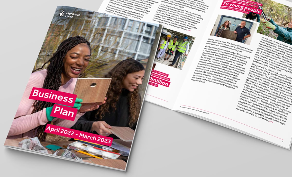 A business plan booklet titled “Business Plan April 2022 - March 2023” for the National Lottery Heritage Fund. The cover features a smiling woman working on a project with another person. The booklet is open to a page discussing the impact of their programs, including support for 70 young people from diverse backgrounds.
