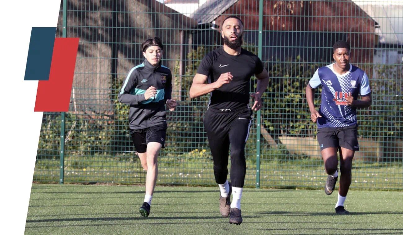 Three individuals are running on a sports field, captured mid-stride.