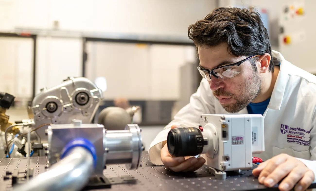 A researcher from Loughborough University examines advanced engineering equipment in a laboratory.