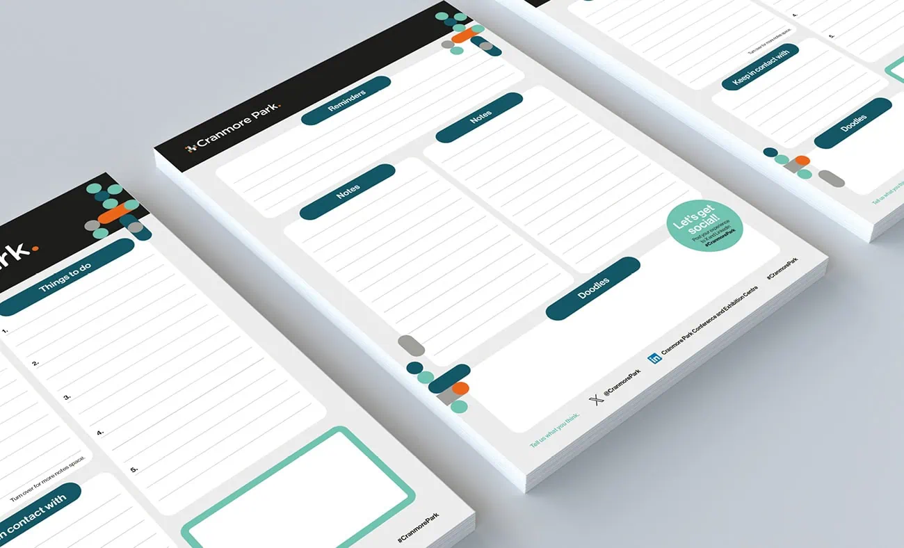 A set of Cranmore Park-branded notepads featuring sections for notes, things to do, and contact details, designed with teal, orange, and grey geometric accents on a clean white background.