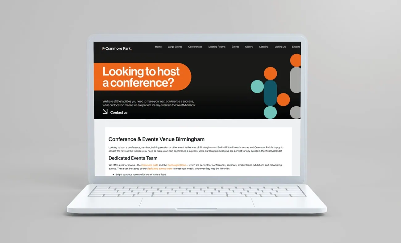 A laptop displaying the Cranmore Park website with a bold header reading "Looking to host a conference?" in orange and white text against a black background, alongside geometric accents in teal, orange, and grey. Below, the page features details about the conference and events venue in Birmingham.