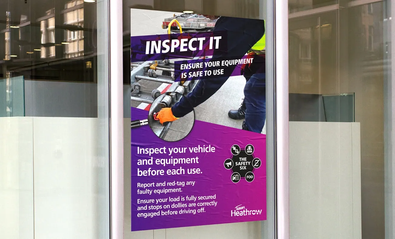 A safety poster titled "INSPECT IT" with the subheading "Ensure Your Equipment Is Safe to Use", displayed on a glass panel. The design features an image of hands inspecting vehicle equipment and includes instructions to check vehicles and equipment before use, report faults, and secure loads. The "Safety Six" icons and Heathrow branding are at the bottom.