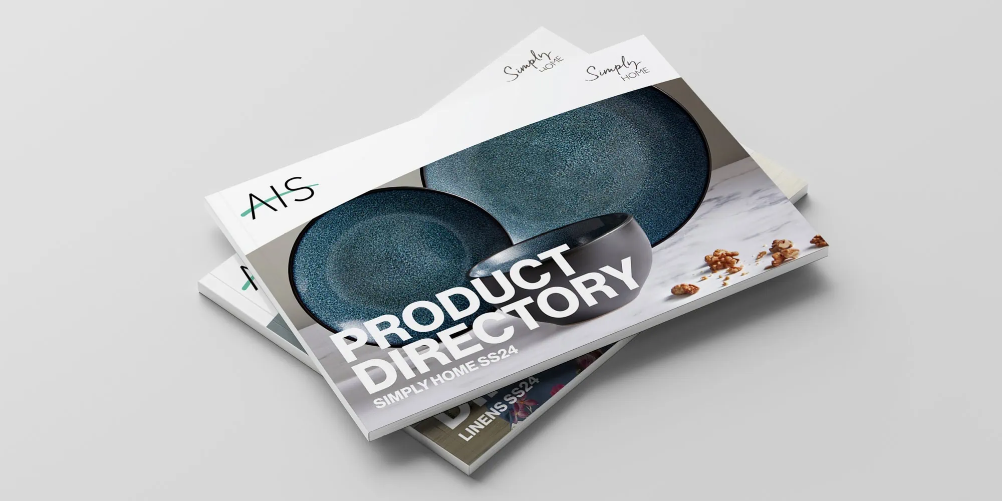 A stack of product directories for AIS, with the top cover featuring stylish blue ceramic bowls and the title "Product Directory: Simply Home SS24" displayed prominently.